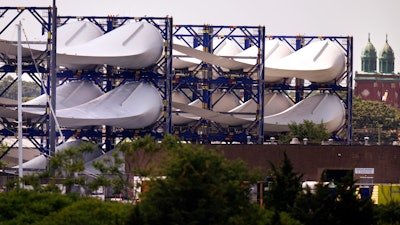 Giant wind turbine blades for the Vineyard Winds project are stacked on racks in the harbor.