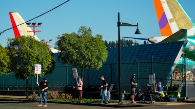 Boeing 737 Max aircrafts are seen behind fences as Boeing employees work the picket line while striking Tuesday, Sept. 24, 2024, next to the company's facilities in Renton, Wash.