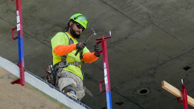 A construction worker installs a safety railing on a new building in Philadelphia, Tuesday, Sept. 3, 2024.