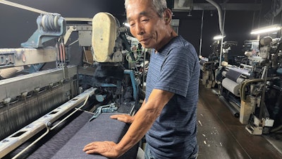 Weaving craftsman Shigeru Uchida examines the evenness of the fabric being woven by the old power looms at Momotaro Jeans in Kojima, Okayama prefecture, Japan, on Sept. 4, 2024.