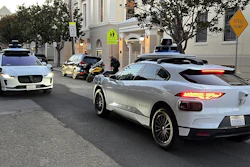 Two Waymo driverless taxis stop before passing one another on a San Francisco street on Feb. 15, 2023.