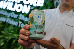 Nick Chow, part of the COP29 Singapore Pavilion team, poses for a photo with NEWBrew, beer made with treated wastewater, during the COP29 U.N. Climate Summit, Friday, Nov. 15, 2024, in Baku, Azerbaijan.