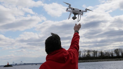 In this April 29, 2018, file photo, a drone operator helps to retrieve a drone after photographing over Hart Island in New York.