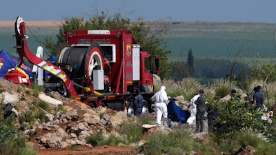 Forensic service workers carry remains in blue body bags during a rescue operation to rescue miners from below ground in an abandoned gold mine in Stilfontein, South Africa, Tuesday, Jan. 14, 2025.