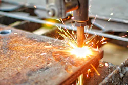 A machine cutting through thick steel with high temperature application.