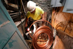 George Philbin, of Boyle & Fogarty Construction, works to feed a new copper residential water supply line, after removing a old lead residential water supply line, in the basement of a home where service was getting upgraded, June 29, 2023, in Providence, R.I.