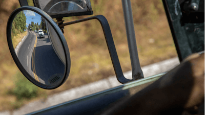 Trucks loaded with avocados are seen reflected on a rear view mirror as they are escorted by the police on their way to the city of Uruapan, in Santa Ana Zirosto, Michoacan state, Mexico, Jan. 26, 2023.