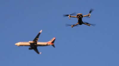 A drone hovers in airspace outside the safety perimeter surrounding St. Louis Lambert International Airport as an airliner approaches for a landing on March 10, 2025.