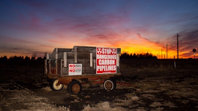 A wagon covered in signs protesting the installation of a Summit Carbon Solutions pipeline stands on a farm in Lake County, S.D., on Monday, March 10, 2025, in one of the counties that the pipeline would cut through.