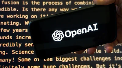 The OpenAI logo appears on a mobile phone in front of a screen showing part of the company website in this photo taken on Nov. 21, 2023 in New York.