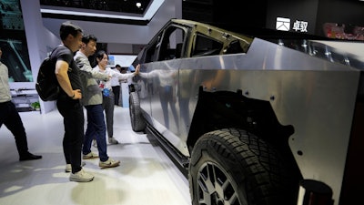 Visitors look at a bare-bones version of Tesla's Cybertruck with devices from AOD Technology, which makes domain control units that process various commands such as opening doors and controlling running boards on SUVs, displayed at the Shanghai auto show on Thursday, April 24, 2025.