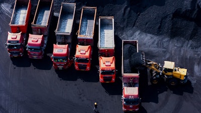 Workers load coal on trucks at a coal yard port on the Yangtze River in southwest China's Chongqing Municipality on Sunday, April 20, 2025.