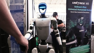A Unitree robot shakes hands with a convention guest at the Robotics Summit & Expo, Wednesday, April 30, 2025, in Boston.