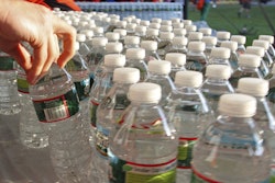 A runner grabs a bottle of water at the athlete's village prior to the start of the 116th running of the Boston Marathon, Hopkinton, Mass., April 16, 2012.