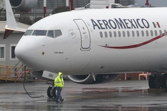 A worker wearing a mask walks past a Boeing 737 Max 9 as it is prepared for a flight from Renton Municipal Airport, Nov. 18, 2020, in Renton, Wash.