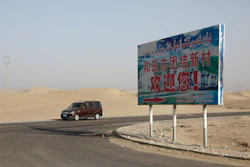 A car drives through a desert where a signboard which reads 'Welcome to the Hotan Unity New Village' is seen on display in Hotan, in western China's Xinjiang region on Sept. 21, 2018.