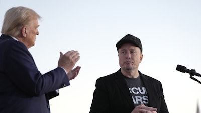 Republican presidential nominee former President Donald Trump, left, claps as Tesla and SpaceX CEO Elon Musk prepares to depart after a campaign event at the Butler Farm Show on Oct. 5, 2024, in Butler, Pa.
