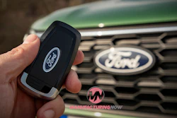 Ford car key and vehicle grille with Ford logo in green background