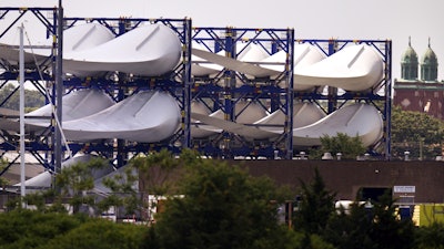 Giant wind turbine blades for the Vineyard Winds project are stacked on racks in the harbor, July 11, 2023, in New Bedford, Mass.