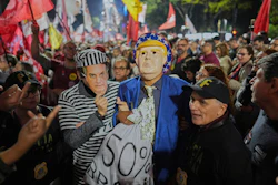 Protesters wearing masks of U.S. President Donald Trump and former President Jair Bolsonaro as a prisoner, protest Trump's announcement of 50% tariffs on Brazilian goods, in Sao Paulo, Thursday, July 10, 2025.