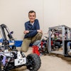 Mechanical engineering professor Dan Negrut poses with a space rover used for testing.