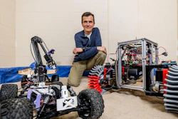 Mechanical engineering professor Dan Negrut poses with a space rover used for testing.