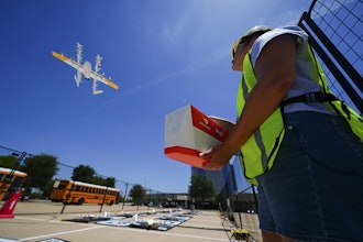 Masslie Arias, of DoorDash, prepares to load a delivery package on a hovering drone Thursday, July 31, 2025, in Frisco, Texas.