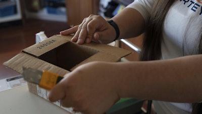 Amanda Follett opens packages at A Sight For Sport Eyes, a brick-and-mortar and e-commerce store for sport goggles, Aug. 20, 2025, in West Linn, Ore.