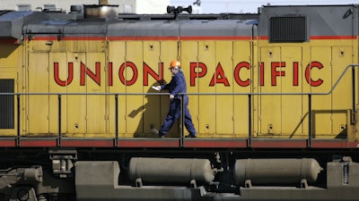 A maintenance worker walks past a locomotive in the Union Pacific Railroad fueling yard in north Denver, Oct. 18, 2006.