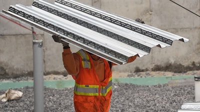 A construction worker carries steel decking at the site of a construction of a housing project, Thursday, July 31, 2025, in Portland, Maine.