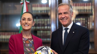 Canada's Prime Minister Mark Carney, right, presents Mexican President Claudia Sheinbaum with an official World Cup soccer ball before they meet at the Palacio National in Mexico City, Thursday, Sep 18, 2025.