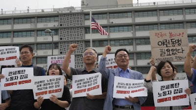 Protesters stage a rally against the detention of South Korean workers during an immigration raid in Georgia, near the U.S. Embassy in Seoul, South Korea, Tuesday, Sept. 9, 2025. The signs read 'A tariff bomb and workers confinement.'