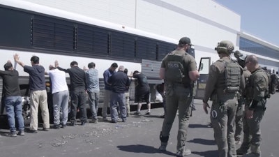 This image from video provided by U.S. Immigration and Customs Enforcement via DVIDS shows manufacturing plant employees waiting to have their legs shackled at the Hyundai Motor Group’s electric vehicle plant, Thursday, Sept. 4, 2025, in Ellabell, Ga.