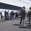 This image from video provided by U.S. Immigration and Customs Enforcement via DVIDS shows manufacturing plant employees waiting to have their legs shackled at the Hyundai Motor Group’s electric vehicle plant, Thursday, Sept. 4, 2025, in Ellabell, Ga.