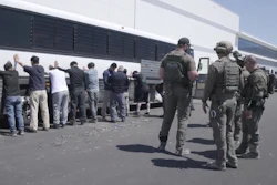 This image from video provided by U.S. Immigration and Customs Enforcement via DVIDS shows manufacturing plant employees waiting to have their legs shackled at the Hyundai Motor Group’s electric vehicle plant, Thursday, Sept. 4, 2025, in Ellabell, Ga.