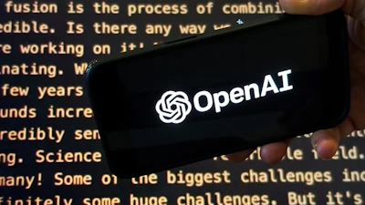 The OpenAI logo appears on a mobile phone in front of a screen showing part of the company website in this photo taken on Nov. 21, 2023 in New York.