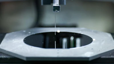 A closeup look at the tiny needle used in the Hummink printing technology. The needle is essentially attached to a tuning fork, which moves the needle rapidly above the printing surface. Natural competing surface energies pull tiny amounts of ink out to print designs with submicrometer precision.