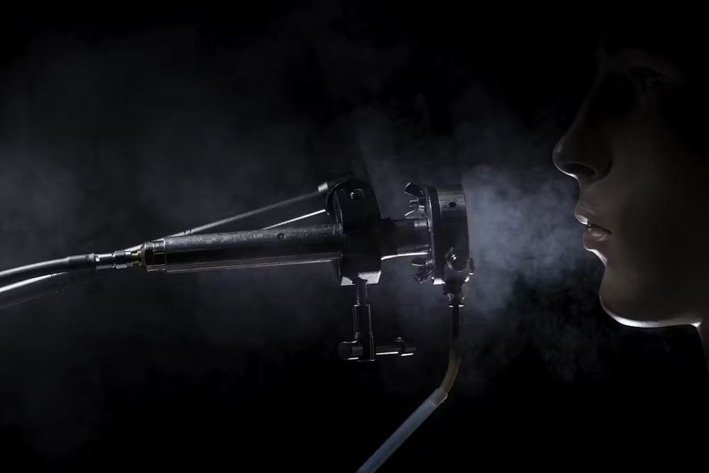 Dark medical device emitting vapor with partial silhouette of person