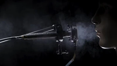 Dark medical device emitting vapor with partial silhouette of person