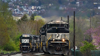 A Norfolk Southern freight train passes a train on a siding as it approaches a crossing in Homestead, Pa, April 27, 2022.