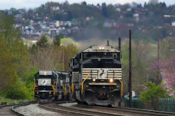 A Norfolk Southern freight train passes a train on a siding as it approaches a crossing in Homestead, Pa, April 27, 2022.