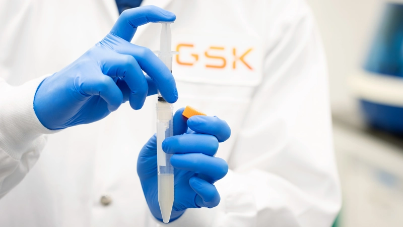 Scientist holding lab syringe in a GSK facility.