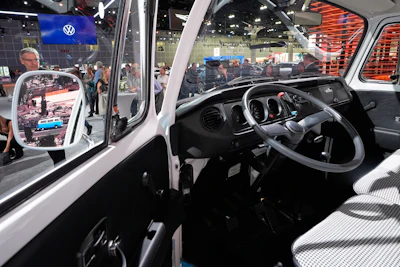 Convention-goers look over the restored VW bus, which had survived the Pacific Palisades fire in January, at the AutoMobility LA car show Thursday, Nov. 20, 2025, in Los Angeles.