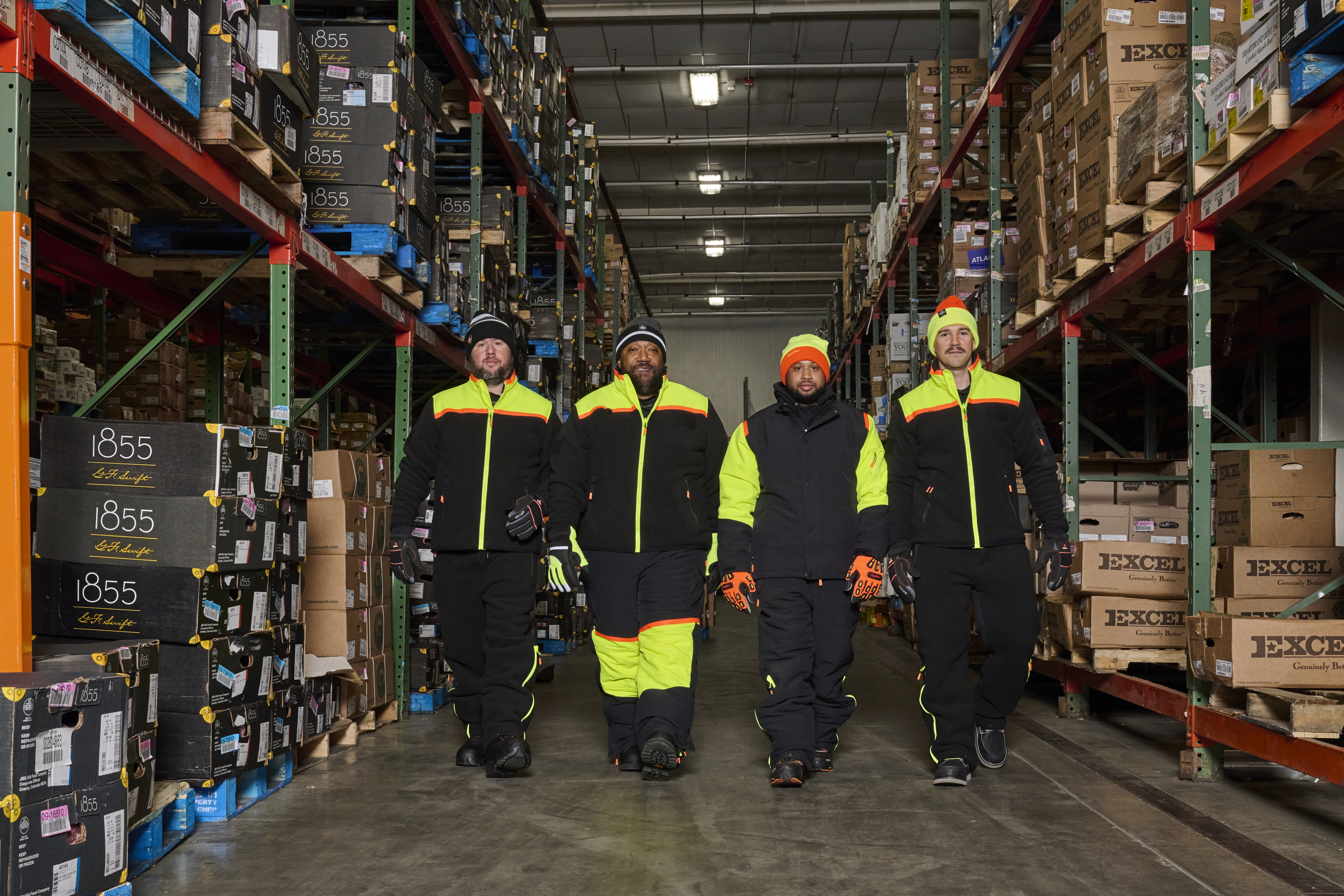 Four employees outfitted with mix-and-match PPE present a united front while staying warm and productive across a range of temperatures in a protein processing and storage facility.