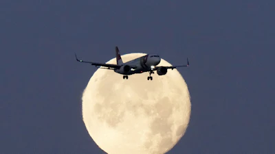 A TAP Air Portugal Airbus A320 is silhouetted against the setting moon while approaching for landing in Lisbon, Portugal, June 23, 2024.
