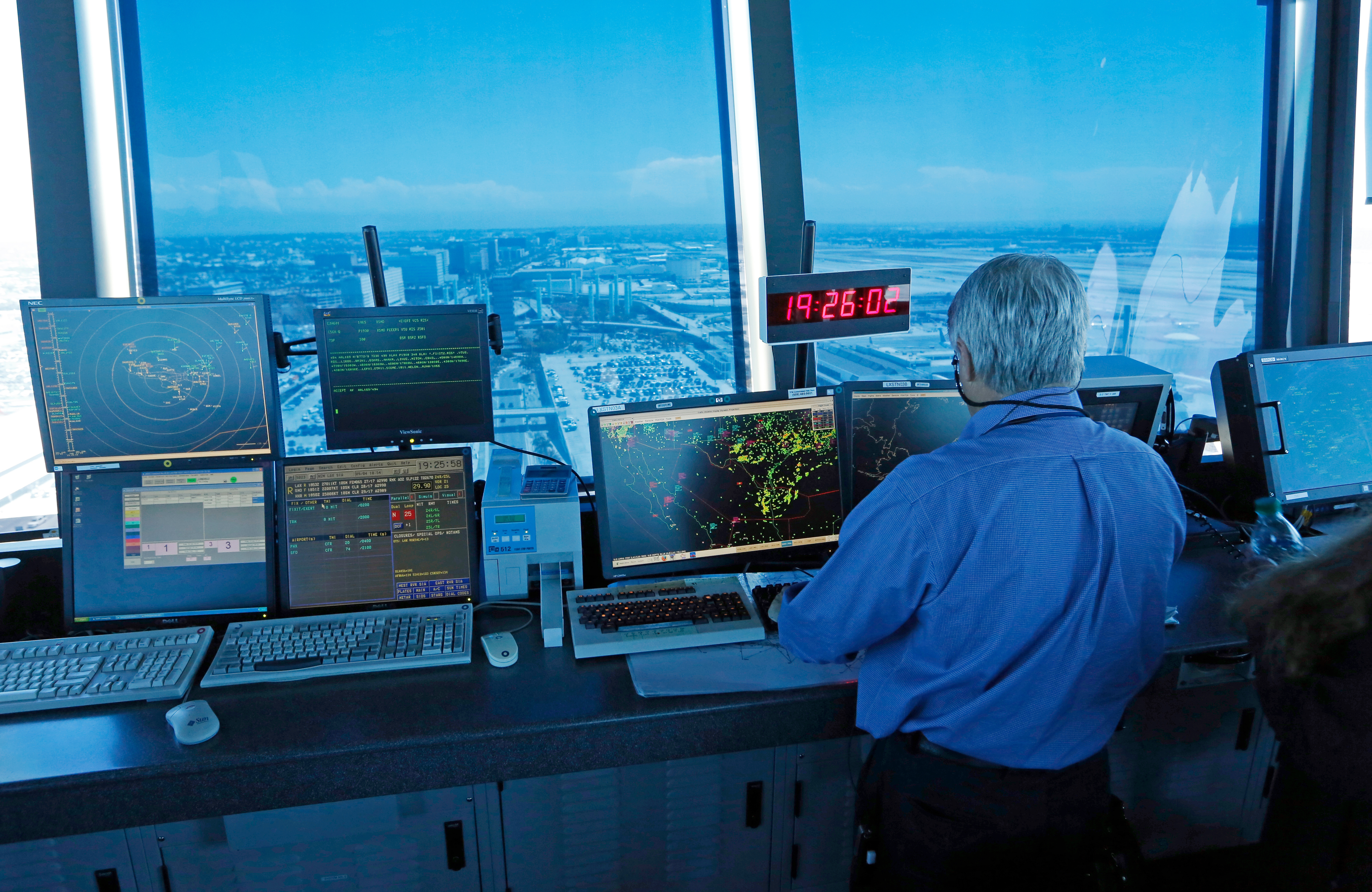 In this Sept. 4, 2013 photo, an air traffic controller works at computer screens and a digital clock showing Coordinated Universal Time (UTC), or Zulu time, is seen in this view looking eastward from the control tower at Los Angeles International Airport (LAX).