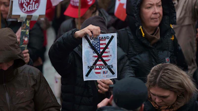 A man holds a map of Greenland covered in the American flag crossed out with an X during a protest against Trump's policy towards Greenland in front of the US consulate in Nuuk, Greenland, Saturday, Jan. 17, 2026.