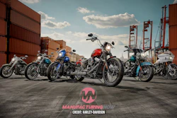 Row of custom motorcycles lined up in a shipping container port yard under blue sky