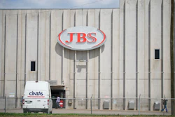 Employees walk in front of the entrance to the JBS meat processing plant, July 23, 2021, in Greeley, Colo.