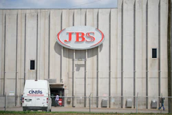 Employees walk in front of the entrance to the JBS meat processing plant, July 23, 2021, in Greeley, Colo.